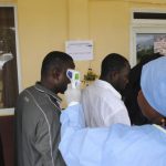 A health worker takes the temperature of people at a news conference outside Monrovia