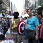 A protester of the Occupy Central movement carries a shield from the 'Captain America' comic book series as he stands on a main road at the Mong Kok shopping district in Hong Kong