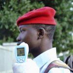 A school official takes a Goverment Secondary School Garki pupil's temperature using an infrared digital laser thermometer in front of the school premises, as school resumes in Abuja