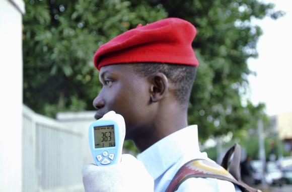 A school official takes a Goverment Secondary School Garki pupil's temperature using an infrared digital laser thermometer in front of the school premises, as school resumes in Abuja