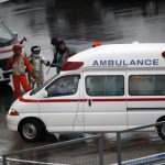 Marshalls clear the way for an ambulance after the race was stopped following a crash by Marussia Formula One driver Bianchi of France at the Japanese F1 Grand Prix at the Suzuka Circuit
