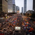 Pro-democracy protesters watch formal talks between student protest leaders and city officials on a video screen near the government headquarters in Hong Kong