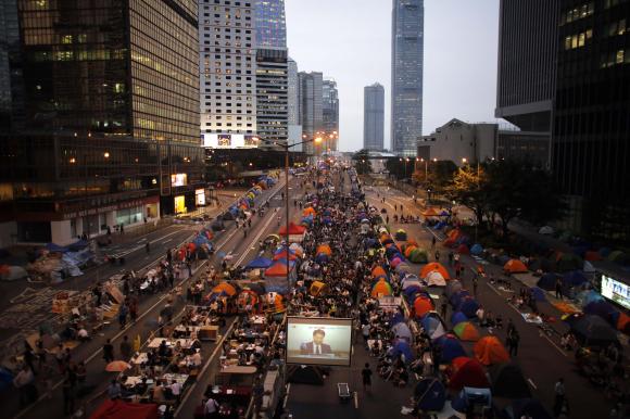 Pro-democracy protesters watch formal talks between student protest leaders and city officials on a video screen near the government headquarters in Hong Kong