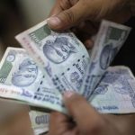 An employee counts Indian currency notes inside a private money exchange office in New Delhi
