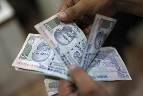 An employee counts Indian currency notes inside a private money exchange office in New Delhi
