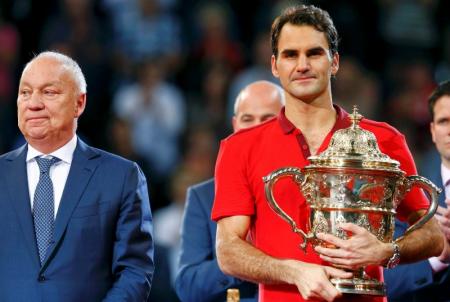 Tournament director Brennwald stands beside as Switzerland's Federer holds the trophy after winning his final match against Belgium's Goffin at the Swiss Indoors ATP tennis tournament in Basel