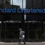 A woman walks past a Standard Chartered bank in London