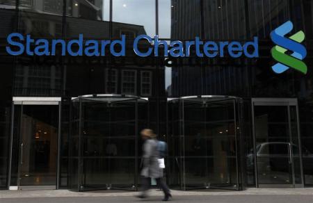 A woman walks past a Standard Chartered bank in London