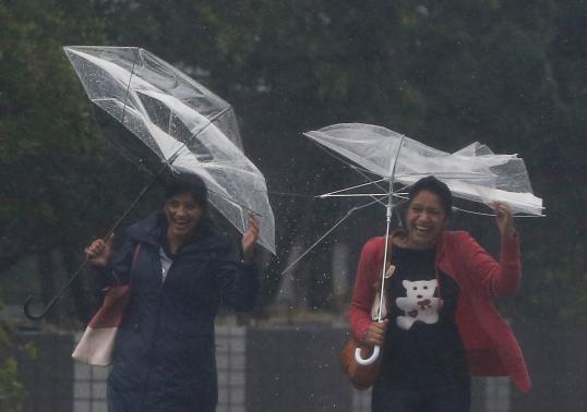 Passers-by with umbrellas struggle against strong winds and heavy rain caused by Typhoon Phanfone, in Tokyo