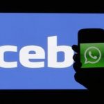 Woman holds a smartphone displaying WhatsApp's logo in front of the screen with the Facebook logo in this photo illustration taken in Prague