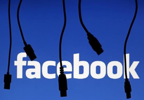 Electronic cables are silhouetted next to the logo of Facebook in this illustration photo in Sarajevo