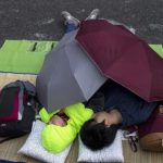 Protesters of the Occupy Central movement sleep under umbrellas early in the morning while protesters block a main road leading to the financial Central district in Hong Kong