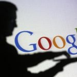 People pose with laptops in front of projection of Google logo in this picture illustration taken in Zenica