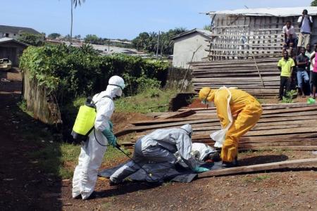 Health workers remove the body a woman who died of Ebola virus in the Aberdeen district of Freetown