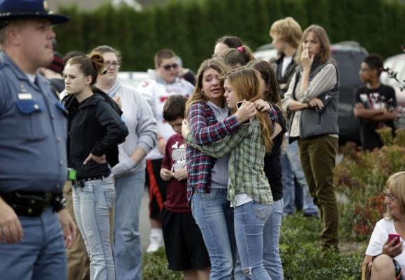 Two girls hug at Shoultes Gospel Hall church where families are reuniting after an active shooter situation at Marysville-Pilchuck High School in Marysville, Washington