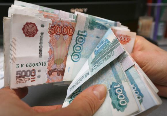 An employee counts Russian rouble banknotes at a small private shop in Krasnoyarsk
