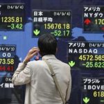 A man looks at an electronic board displaying Japan's Nikkei average and the stock price indexes of various countries outside a brokerage in Tokyo