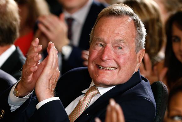 Former President George H. W. Bush applauds during an event to honor the winner of the 5,000th Daily Point of Light Award at the White House in Washington in this file photo