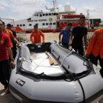 Rescue team members carry an inflatable boat in front of SAR ship KN Purworejo during a search operation for passengers of AirAsia flight QZ8501 at Kumai port in Pangkalan Bun