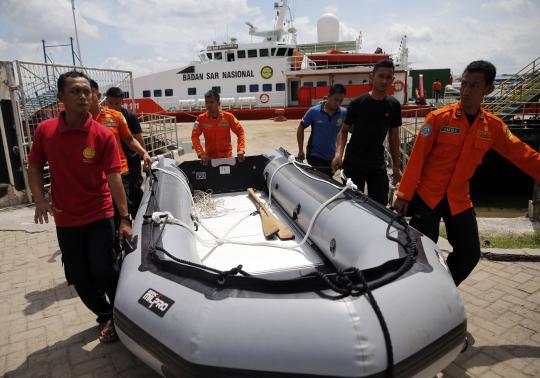 Rescue team members carry an inflatable boat in front of SAR ship KN Purworejo during a search operation for passengers of AirAsia flight QZ8501 at Kumai port in Pangkalan Bun
