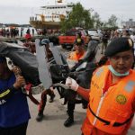 Rescue team members walk as they carry the wreckage of a seat of the AirAsia Flight QZ8501 airliner at Kumai port