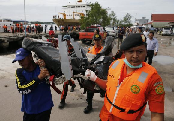 Rescue team members walk as they carry the wreckage of a seat of the AirAsia Flight QZ8501 airliner at Kumai port