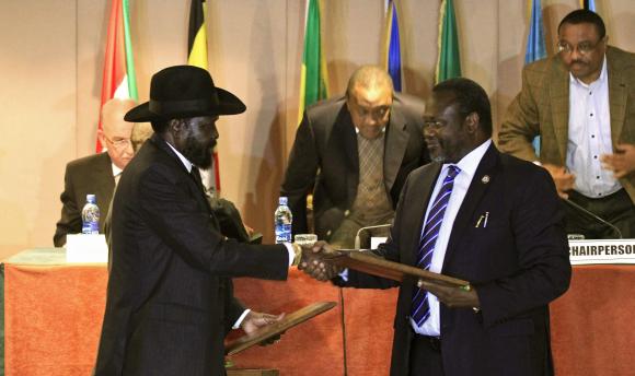 South Sudan's President Kiir and South Sudan's rebel commander Machar exchange documents fter signing a ceasefire agreement during the IGAD Summit in Addis Ababa