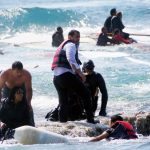 Local residents and rescue workers help a migrant woman