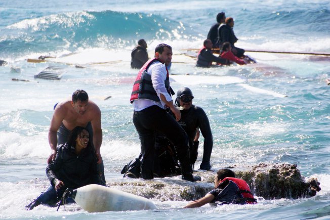 Local residents and rescue workers help a migrant woman