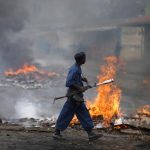 A policeman walks in front of a burning barricade during a protest against Burundi's President Pierre Nkurunziza and his bid for a third term in Bujumbura