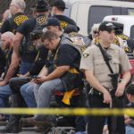 A sheriff's deputy stands guard near a group of bikers in Waco
