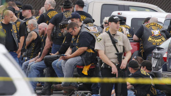 A sheriff's deputy stands guard near a group of bikers in Waco