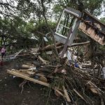 Amy Gilmour a volunteer from San Antonio Texas walks past a pile of debris which included parts of destroyed homes that amassed when the Blanco River flooded during the Memorial Day weekend rains in Wimberley Texas