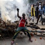 A protester sits in front of a burned barricade during a protest against Burundi President Pierre Nkurunziza and his bid for a third term in Bujumbura