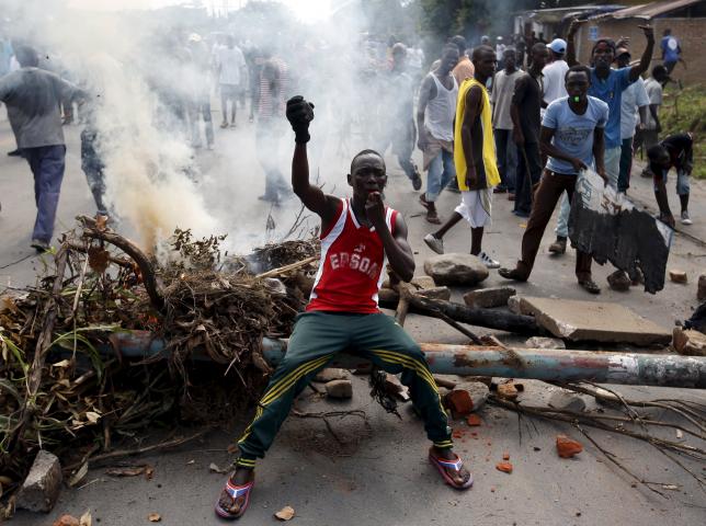 A protester sits in front of a burned barricade during a protest against Burundi President Pierre Nkurunziza and his bid for a third term in Bujumbura