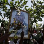 Supporters of Nkurunziza carry his picture as they wait him to return to the capital, at a street in Bujumbura