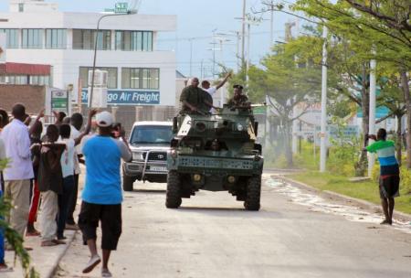 Soldiers patrol the streets in a military vehicle as civilians celebrate in Burundi's capital Bujumbura