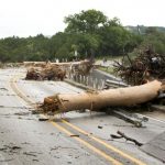 Trooper Marcus Gonzales walks on the Highway 12 bridge over the Blanco River which was blocked by large trees after flooding in Wimberly, Texas