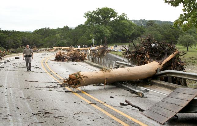 Trooper Marcus Gonzales walks on the Highway 12 bridge over the Blanco River which was blocked by large trees after flooding in Wimberly, Texas