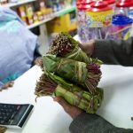 A man holds bundles of khat in Harlesden