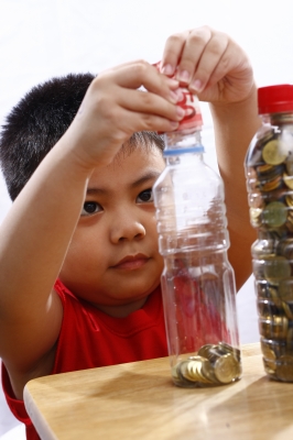 Little Boy Putting Money In A Bottle