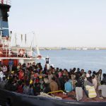 Migrants wait to disembark in the Sicilian harbour of Augusta