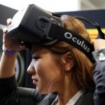 A woman puts on an Oculus virtual reality headset during preparations for the 2014 LA Auto Show in Los Angeles