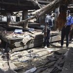police officers inspect the site of a suicide bomb attack at a cattle market