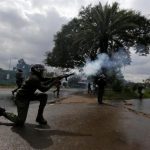 A riot policeman lobs a teargas canister to disperse supporters of the CORD during a protest at the premises hosting the headquarters of IEBC to demand the disbandment of the electoral body ahead of next year's election in Nairobi
