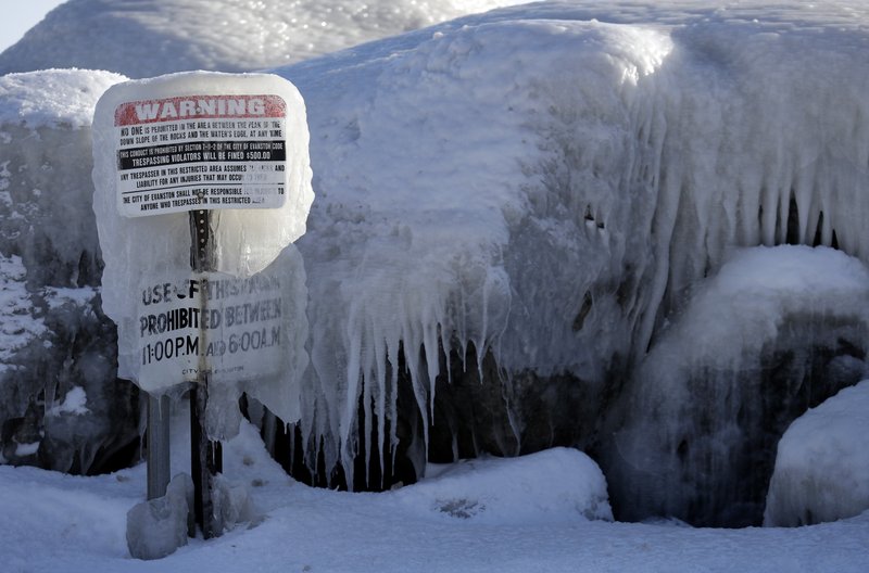 A warning sign is covered by ice at Clark Square park in Evanston