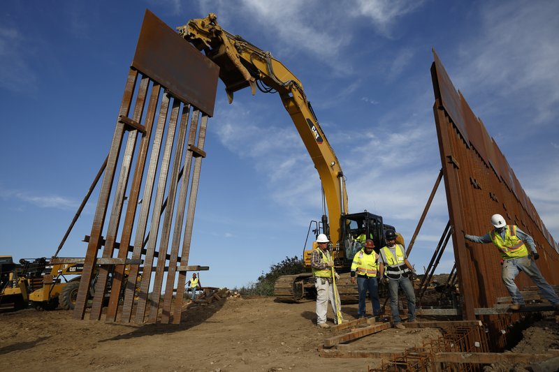 Construction crews install new border wall sections seen from Tijuana