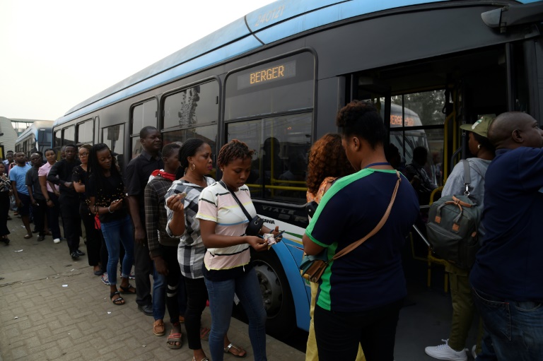 Passengers queue to board a bus in Lagos