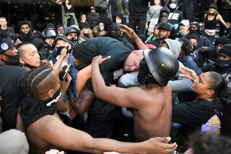 A man is lifted up and taken to police lines after being beaten in clashes between protesters supporting the Black Lives Matter movement