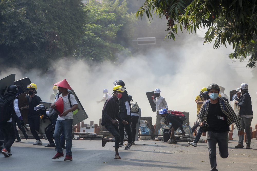 Anti-coup protesters run from teargas and charging riot police and soldiers in Mandalay, Myanmar